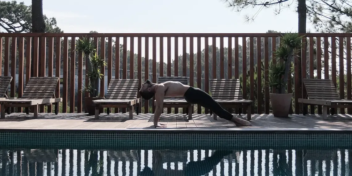 man in yogapose bij zwembad