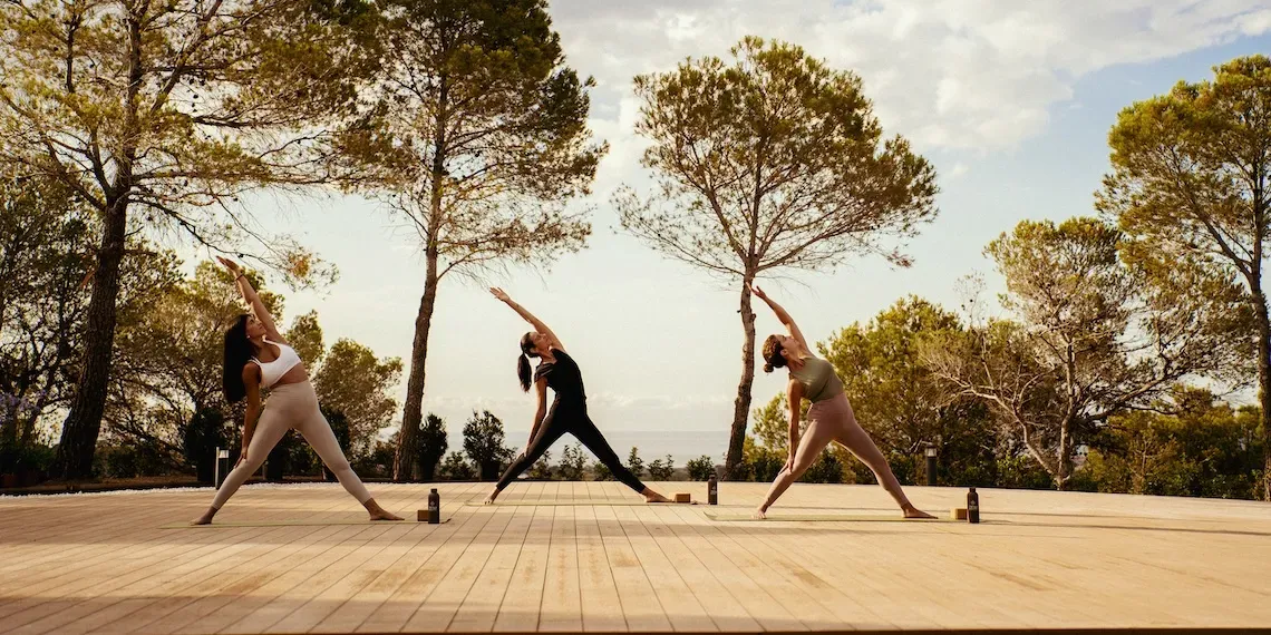 drie vrouwen in yoga pose op buiten deck met bomen