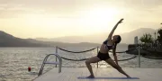 vrouw doet yogapose op een platform aan zee