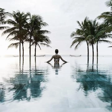 vrouw in zwembad met palmbomen